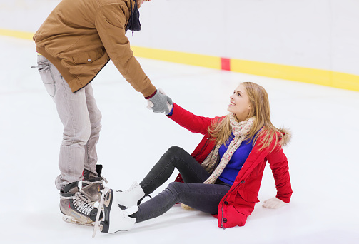 man helping women to rise up on skating rink